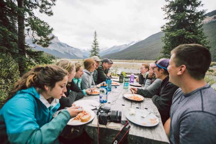 Students eat at a picnic table with Associate Professor Erich Osterberg at the Beauty Creek Hostel in Banff National Park.