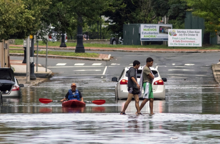 Pedestrians walk across Hanover Street in Meriden, Conn. on July 9 as a kayaker floats along after Tropical Storm Elsa moved through the state. 