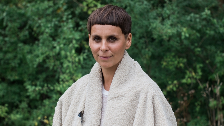 Ash Fure wearing a fleece coat in front of green foliage.