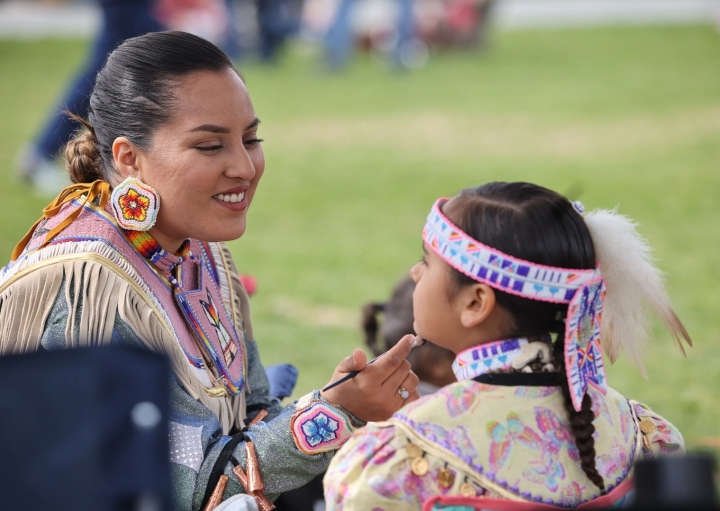 A woman painting a child's face at the Powwow