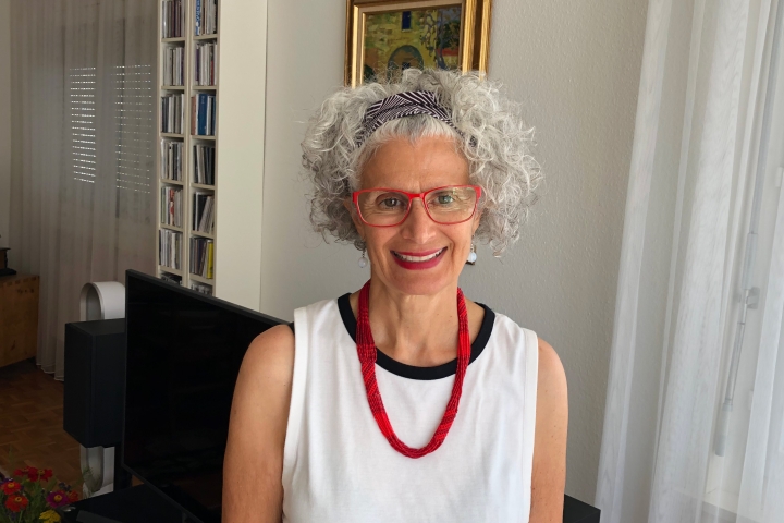 Kacandes in a white sleeveless blouse and bright red necklace