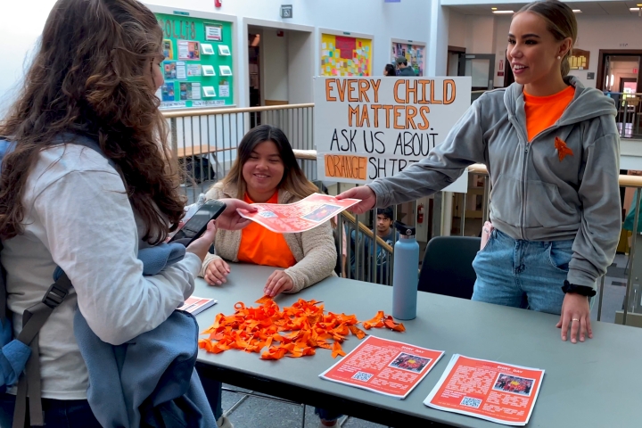 Students hand out information about Orange Shirt Day.