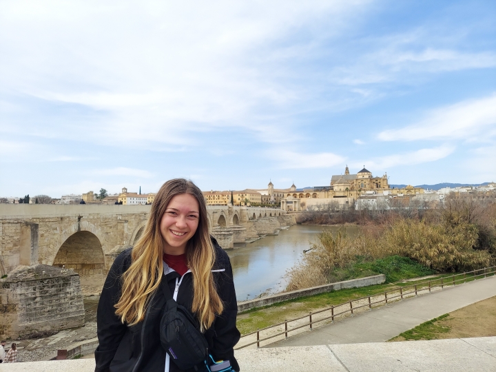 Samantha Palermo in front of a historic Roman bridge in Spain