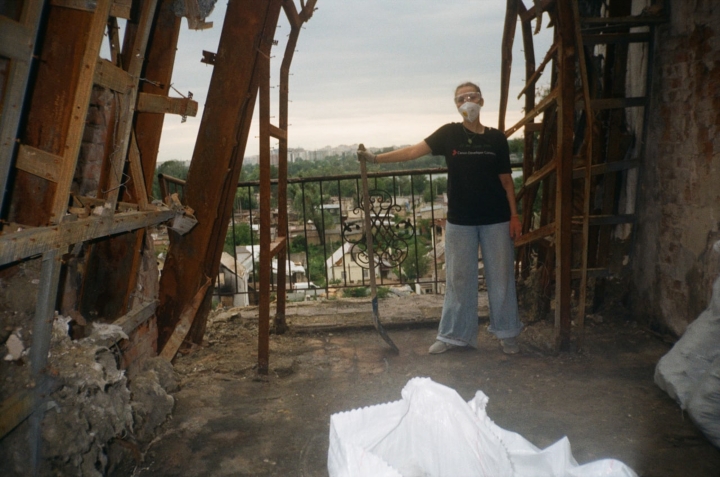 tonia Zakorchemna holding a shovel amidst rubble and destruction