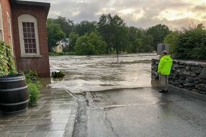 Workers watches flooding of Ottauquechee River