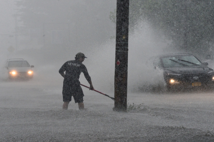 Worker tries to clear flooded road in southern Vermont rainstorm