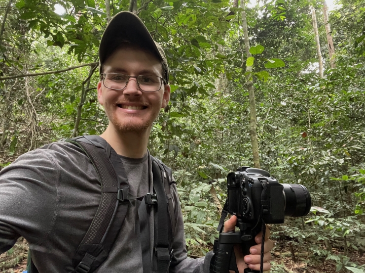 Luke Fannin in the jungle holding a camera.