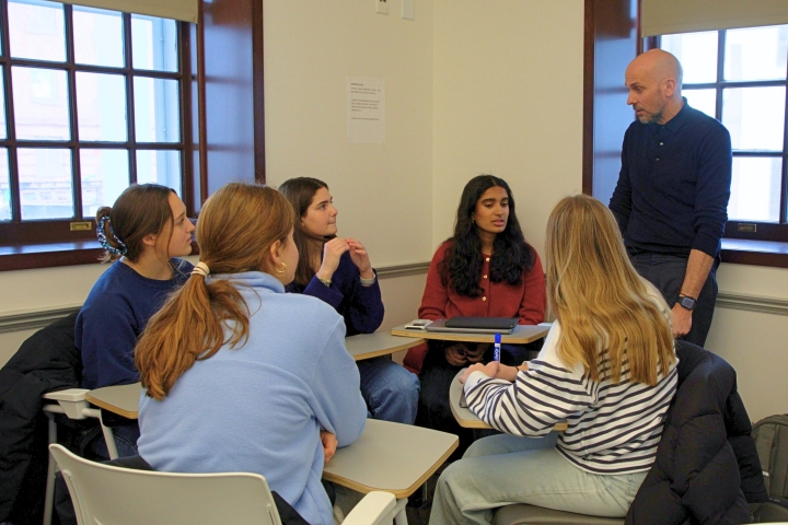 Students sit in a circle speaking to a professor