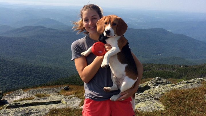 Catherine Gordon holding her dog while standing at the top of a mountain