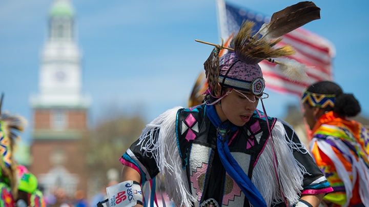 a Native American dancer in black and pink regalia with fringe and feathers