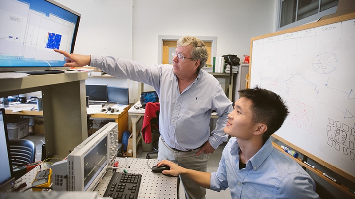 Eric Fossum and a student working at a computer together