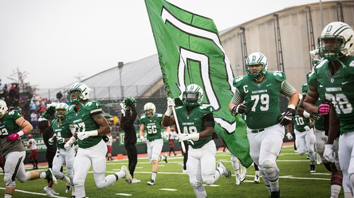 football players carrying a Dartmouth flag