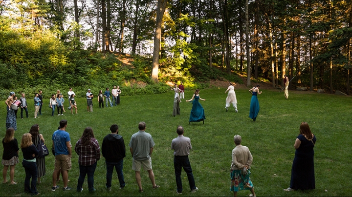 Actors on stilts rehearsing outside in a wooded area