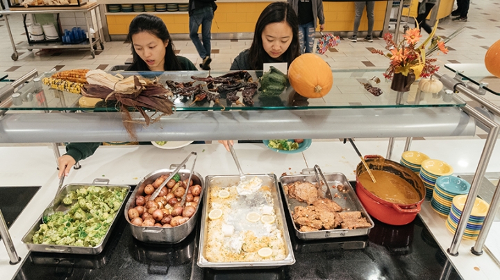 two female students getting food from a buffet