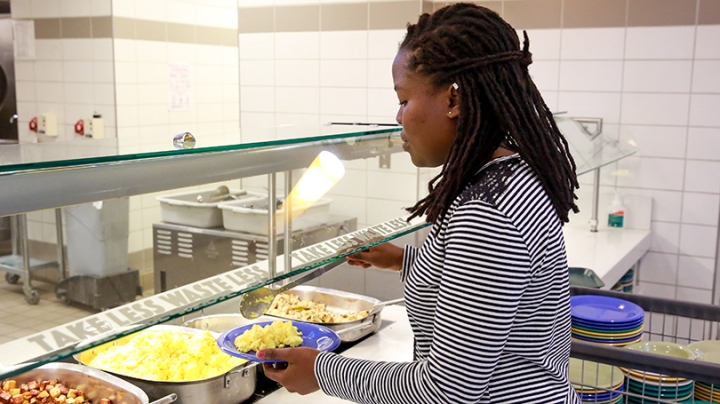 a student filling her plate with scrambled eggs in 53 Commons dining hall