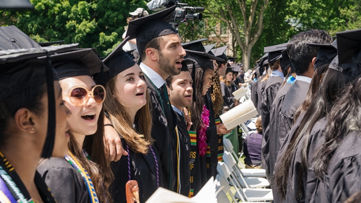 Students sing the alma mater at commencement.