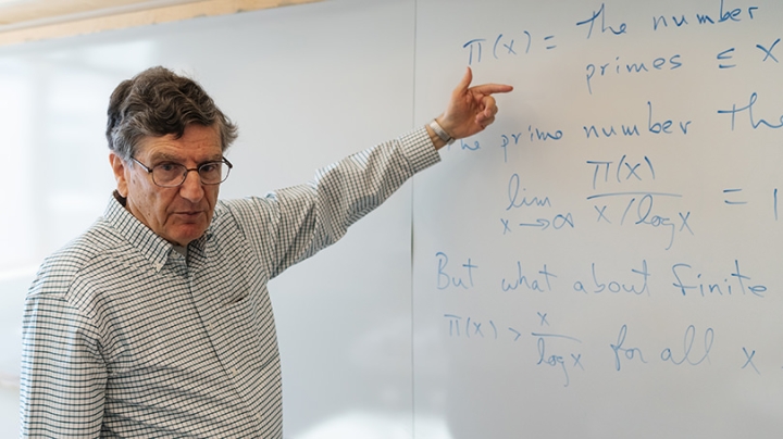 Mathematics professor emeritus Carl Pomerance points to a whiteboard