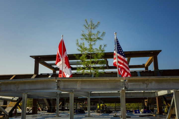 Culminating the topping-off ceremony, workers lower the beam into place.