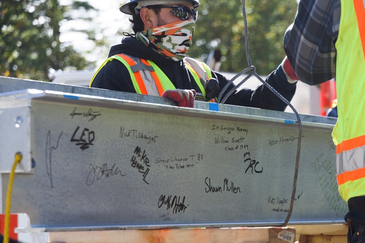 Construction workers, administrators, and faculty put their signatures on the building's final beam, a topping-off tradition.