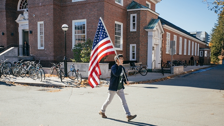 a student carrying the American flag across campus