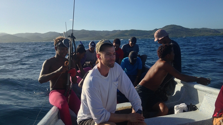 Tyler Pavlowich sitting in a boat with a group of fishermen