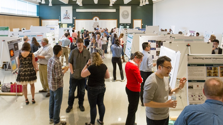 a crowd of people and displays of graduate research posters inside Alumni Hall at Dartmouth