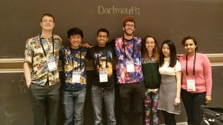 six students standing together in front of a blackboard with Dartmouth written on it in chalk