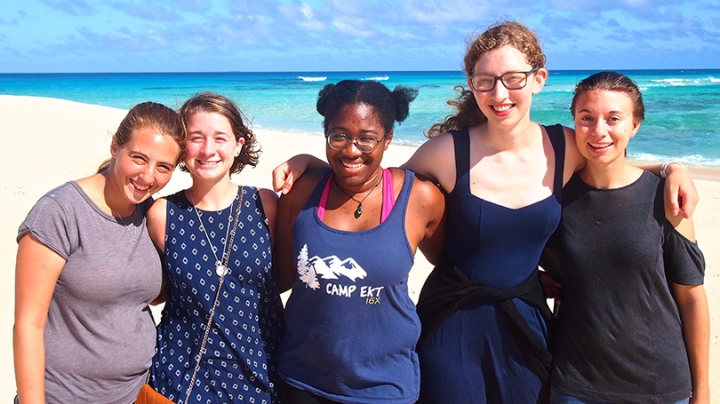 a group of female students standing together on a beach