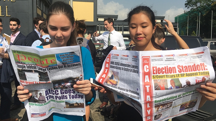 two female students reading newspapers