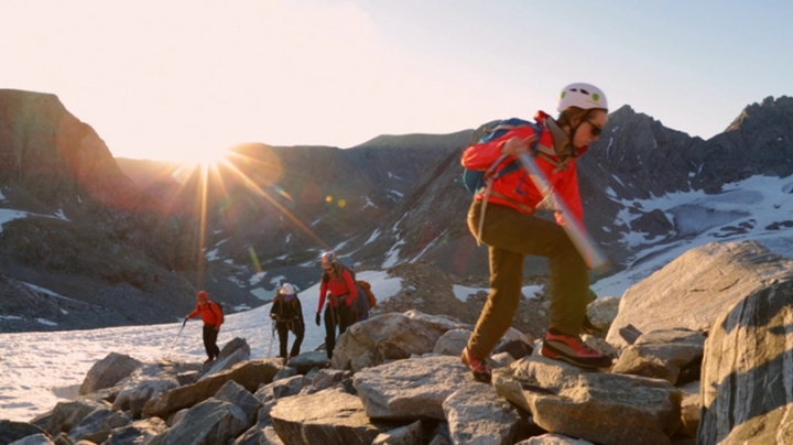 people in red jackets climbing rocks on a mountain