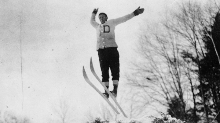 a black and white photo of a skier soaring through the air after a jump at the 1911 Winter Carnival
