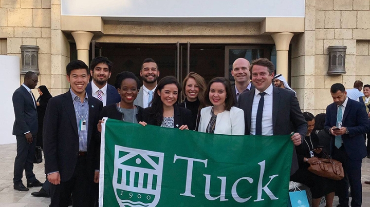 Students posing with a Tuck banner at the World Government Summit in Dubai