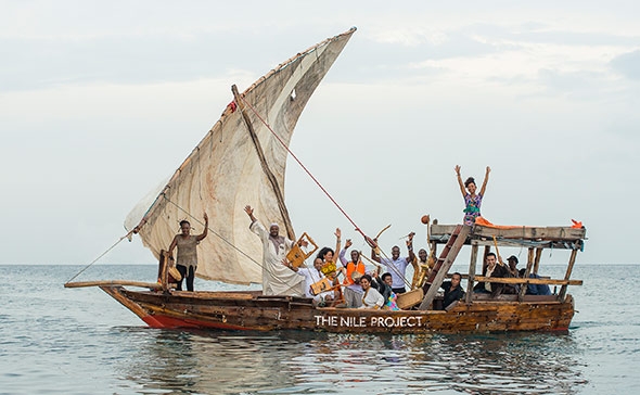 An old wooden sailboat with passengers happily waving