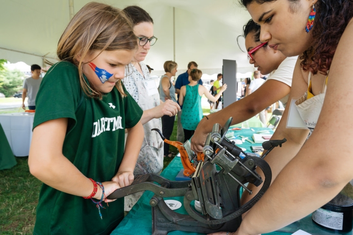 Saba Maheen ’20, right, guides a young Patriots fan in the creation of a souvenir letterpress coaster. Working alongside them are Book Arts Workshop Program Manager Sarah Smith, second from left, and Iliana Godoy ’20. (Photo by Eli Burakian ’00)