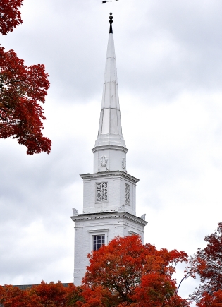 Chuch steeple surrounded by bright red leaves