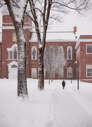 Student walking a snow-covered path from Baker Library