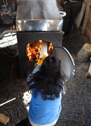 Student feeds the fire that boils the sap.