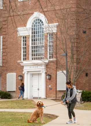Erica Simon '25 and Goldendoodle Chi outside Baker Library
