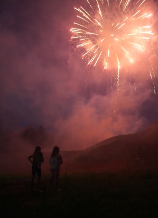 Two children stand and watch fireworks